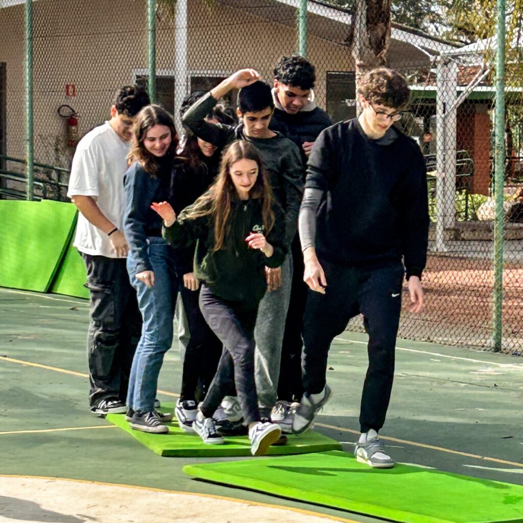 Grupo de jovens em atividade com tatames, trilhando uma caminhada.