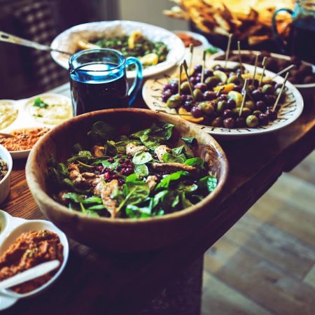 Mediterranean antipasti featuring olives, spinach salad, and dips on a rustic wooden table.