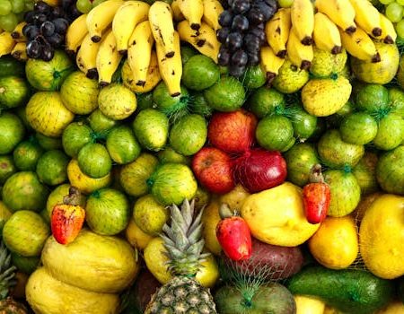 A colorful arrangement of assorted tropical fruits including bananas, apples, pineapples, and citrus.